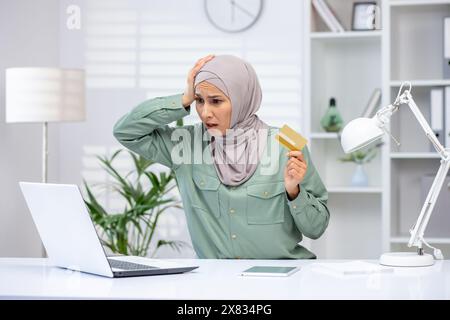 Betrügerische Frau im Hijab, die versucht, einen Online-Kauf zu tätigen, Geschäftsfrau, die eine Bankkreditkarte hält, Fehler beim Geldtransfer zurückgewiesen hat, betrügerische Handlungen. Stockfoto