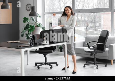 Junge Sekretärin, die Dokumente mit Schredder im Büro vernichtet Stockfoto