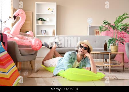Männlicher Tourist mit aufblasbarer Matratze, der zu Hause im Urlaub liegt Stockfoto