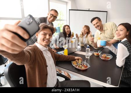 Gruppe von Geschäftsleuten, die während des Mittagessens im Büro Selfie machen Stockfoto