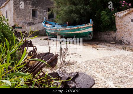 Altes Boot im Innenhof der ehemaligen Tonnara di Scopello mit den eisernen Ankern, die einst zur Positionierung der Thunfischfalle verwendet wurden, Sizilien Stockfoto