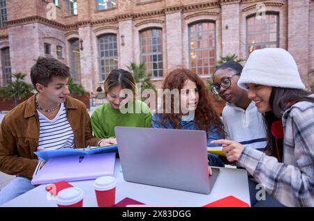 Gruppe lächelnder und konzentrierter Schüler mit Laptop. Brainstorming an der Universität Stockfoto