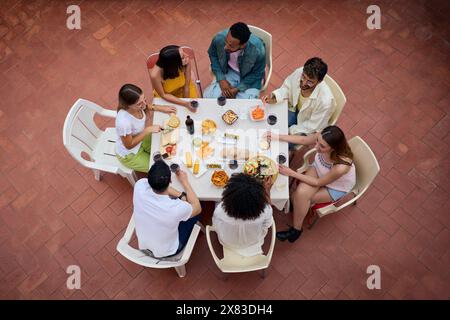 Blick von oben auf eine Versammlung von Menschen um einen Tisch mit Gläsern Wein und Essen Stockfoto