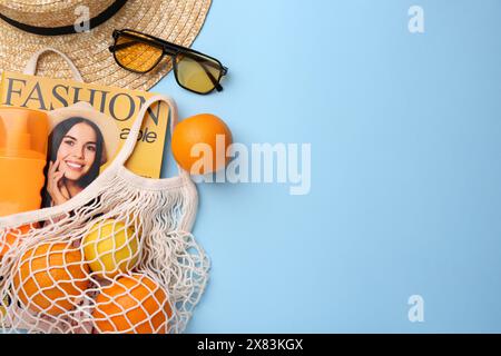 Schnur-Tasche mit Magazin, Obst und Sommeraccessoires auf hellblauem Hintergrund, flach gelegt. Leerzeichen für Text Stockfoto