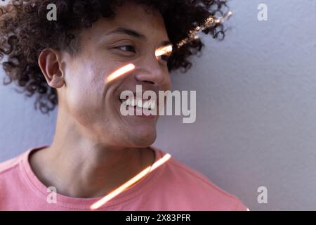 Ein birassischer junger Mann, der ein rosa Hemd trägt und draußen lächelt Stockfoto