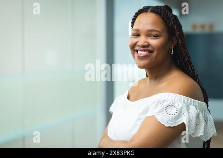 Im modernen Büro für Geschäftsleute lächelt eine junge Frau mit langen geflochtenen Haaren, Kopierraum Stockfoto