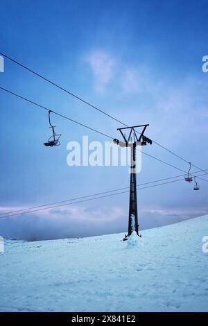 Skilift im Schnee mit einem stimmungsvollen blauen und rosa Himmel dahinter Stockfoto