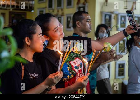 Bangkok, Thailand. Mai 2024. Zwei junge Thailändische Frauen, die während der Kerzenlichtprozession am Tag von Visakha Bucha im Lat Phrao Tempel in Bangkok, Thailand, ein Selfie nahmen. Visakha Bucha, einer der wichtigsten buddhistischen Feiertage Thailands, erinnert an die Geburt, Erleuchtung und den Tod von Gautama Buddha, alles am selben Tag. Thailändische Buddhisten besuchen in der Regel Tempel, um Verdienste zu machen. Dazu gehören Aktivitäten wie Almosen an Mönche, das Hören von Predigten und die Teilnahme an verschiedenen religiösen Ritualen. Quelle: SOPA Images Limited/Alamy Live News Stockfoto