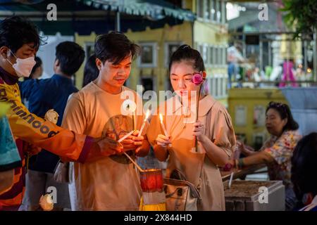 Bangkok, Thailand. Mai 2024. Ein thailändisches Paar sah Kerzen am Tag von Visakha Bucha im Lat Phrao Tempel, der sich in einer einkommensschwachen Gemeinde in Bangkok, Thailand, befindet. Visakha Bucha, einer der wichtigsten buddhistischen Feiertage Thailands, erinnert an die Geburt, Erleuchtung und den Tod von Gautama Buddha, alles am selben Tag. Thailändische Buddhisten besuchen in der Regel Tempel, um Verdienste zu machen. Dazu gehören Aktivitäten wie Almosen an Mönche, das Hören von Predigten und die Teilnahme an verschiedenen religiösen Ritualen. (Foto: Nathalie Jamois/SOPA Images/SIPA USA) Credit: SIPA USA/Alamy Live News Stockfoto