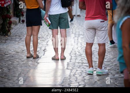 Rua Direita, Óbidos, Portugal. Sandelbedeckte Touristen mit Reiseführer in der Hand auf der Rua Direita, der Hauptstraße aus dem 13. Jahrhundert, die von der Porta da Vila (Haupteingang der Stadt) bis zur Burg von Óbidos (Pousada do Castelo de Óbidos) führt. Stockfoto