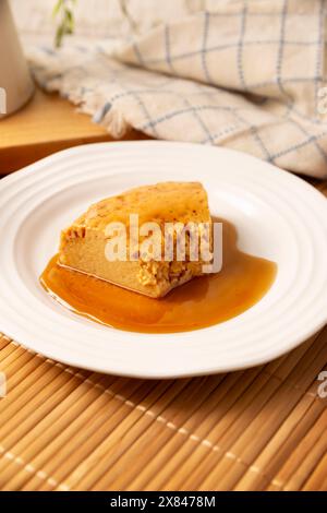 Hausgemachtes Flan Dessert, auch bekannt als Creme Caramel, Karamell Pudding oder Eierpudding, serviert auf weißem Teller auf Holztisch. Stockfoto