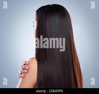 Frau, Haare und Schönheit im Studio von hinten, Keratin-Behandlung und Schulter auf blauem Hintergrund. Hand, gestreckte und weibliche Person mit Wachstum für Stockfoto