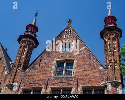 Fassade eines alten Gebäudes mit markanten gotischen Türmen und grünen Fensterläden unter klarem Himmel, alte historische Hausfassaden mit Türmen und Brücken durch A Stockfoto