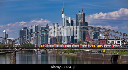 Main mit Regionalbahn auf der Deutschherrnbrücke und einem Frachtschiff vor der Skyline von Frankfurt am Main, Hessen Stockfoto