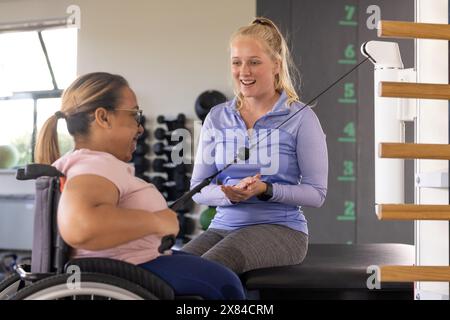 Eine birassische Querschnittsgelähmte Patientin und kaukasische Therapeutin-Übung im Reha-Zentrum Stockfoto