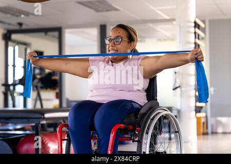 Im Rehabilitationszentrum, birassische Patientin mit Brille, Übungen mit Widerstandskörper Stockfoto