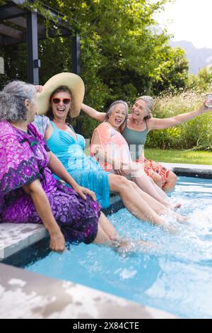 Verschiedene ältere Freundinnen lachen draußen am Pool Stockfoto