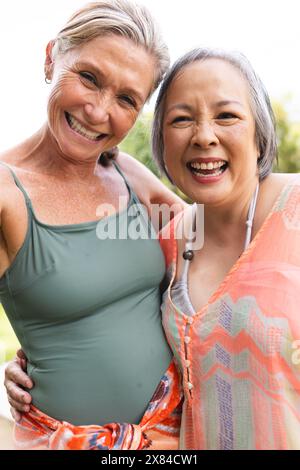 Draußen, verschiedene ältere Freundinnen umarmen, lächeln Stockfoto