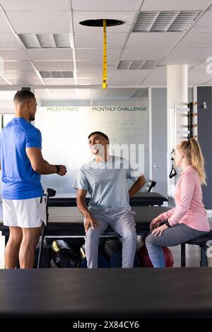 Im Rehabilitationszentrum helfen verschiedene Physiotherapeuten männlichen Patienten Stockfoto