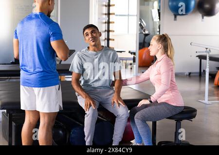 Im Rehabilitationszentrum helfen verschiedene Physiotherapeuten männlichen Patienten Stockfoto