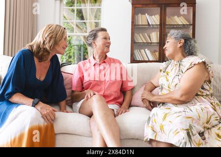 Verschiedene ältere Freundinnen sitzen und plaudern zu Hause auf dem Sofa Stockfoto