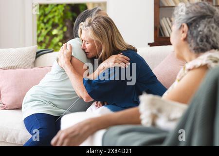 Verschiedene ältere Freundinnen trösten sich zuhause auf der Couch Stockfoto