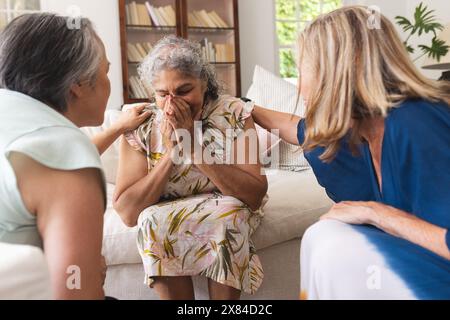 Verschiedene ältere Freundinnen trösten weinende birassische Frau zu Hause Stockfoto