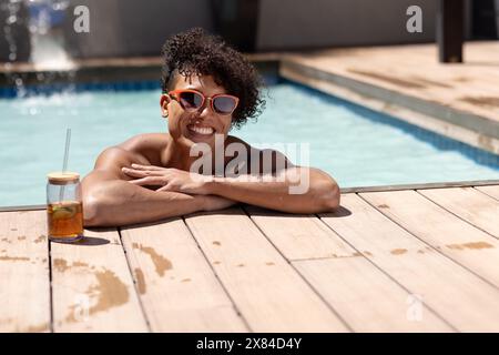 Ein birassischer junger Mann, der sich draußen am Pool, Kopierraum entspannt Stockfoto