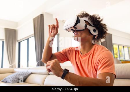Zu Hause erkundet der männliche Mann mit dem VR-Headset neue Welten und zeigt Stockfoto