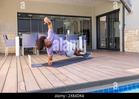 Ein birassischer junger Mann, der draußen in der Nähe des Pools trainiert Stockfoto