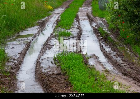 Abgebrochene Feldstraße in den Frühlingsbergen mit vielen schlammigen Pfützen nach dem Regen. Stockfoto