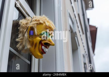 Basel, Schweiz 28. Februar. 2023: Karnevalsmaske, die als Dekoration vor dem Fenster hängt - eine Tradition des Basler Karnevals - UNESCO-Weltkulturerbe Stockfoto