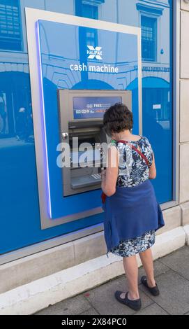Frau, die Bargeld an einem Geldautomaten in Halifax in Leeds, West Yorkshire, England, Großbritannien abhebt Stockfoto