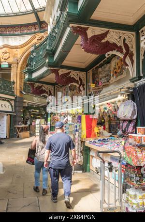 Kunden passieren einen kunstvoll dekorierten Stand in Leeds Kirkgate Market, West Yorkshire, England, Großbritannien Stockfoto