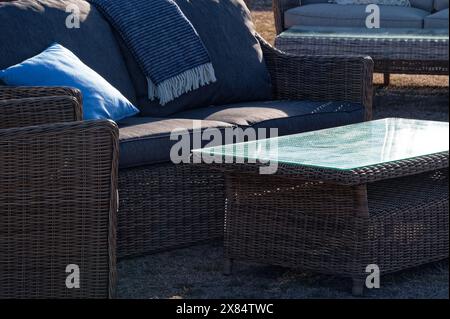 Eine Korbcouch, ein Sitz und ein Couchtisch mit Glasplatte warten darauf, benutzt zu werden. Stockfoto