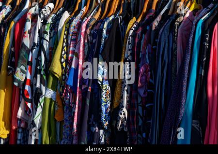 Verschiedene Kleidungsstücke, Kleider, Blusen und Hemden hängen auf einem Regal auf einem Markt Stockfoto