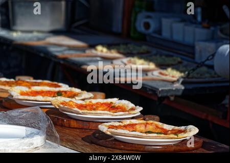 Einige Pizzen stehen zum Verkauf bereit, andere im Hintergrund werden gerade vorbereitet Stockfoto