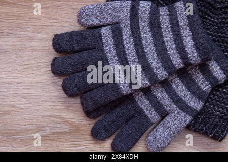Graue Handschuhe und Hut gestrickt für Jungen auf hölzernem Hintergrund Stockfoto