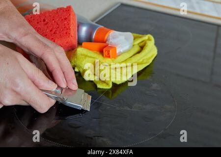 Reinigen Sie das Elektrokochfeld nach der Reinigung mit einem Schaber für Keramikkochfeld Stockfoto