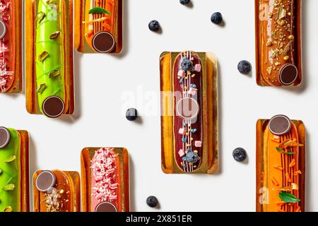 Köstliche Eclairs mit farbenfroher Glasur und verschiedenen Belägen auf weiß Stockfoto