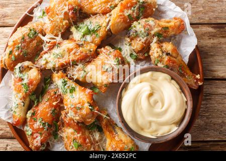 Petersilie Knoblauch Parmesan Hähnchenflügel serviert mit Dippsoße in Nahaufnahme auf einem Teller auf dem Tisch. Horizontale Draufsicht von oben Stockfoto