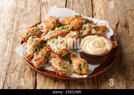 Petersilie Knoblauch Parmesan Hähnchenflügel serviert mit Dippsoße in Nahaufnahme auf einem Teller auf dem Tisch. Horizontal Stockfoto