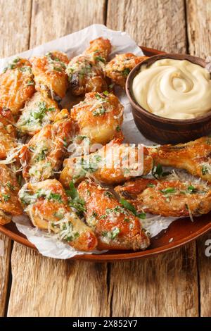 Hausgemachte, gebratene Parmesan Chicken Wings mit Dipping Sauce aus nächster Nähe auf dem Teller auf dem Tisch. Vertikal Stockfoto