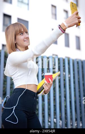 Vertikales Porträt individuelle glückliche junge Frau, die ein Selfie mit Smartphone macht. Stockfoto