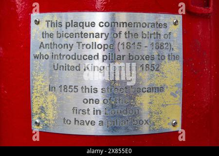Nahaufnahme einer kleinen Tafel auf einem roten Briefkasten, auch als Stumpenkasten bezeichnet, auf Piccadilly in London, die beschreibt, dass es sich um einen der ersten Stumpenkästen handelt. Stockfoto