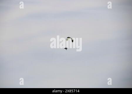 Ein motorisierter motorisierter Gleitschirmflieger, der gegen den blauen Himmel im Freien fliegt, Extremsportarten, Paragliding-Sport Stockfoto