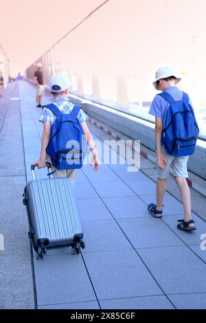 Zwei Kinder mit Koffer, junger Reisender, Jungen von 8-10 Jahren mit Rucksäcken auf der Außenterrasse des Flughafens, Konzept des Urlaubs, lange Reise, AI Stockfoto