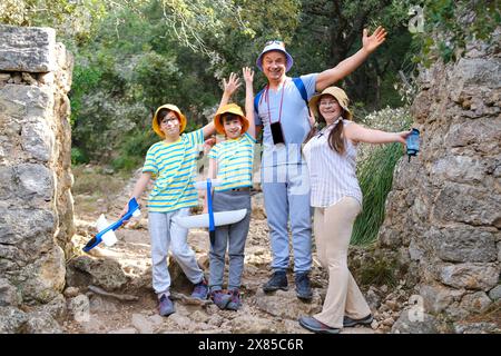 Fröhliche traditionelle Familie mit zwei Kindern im Alter von 8-10 Jahren geht auf eine Wanderung entlang felsiger Bergpfade, reifer gebräunter Mann, Frau, zwei Jungen überwinden Schwierigkeiten Stockfoto