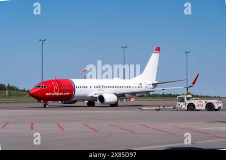 Norwegian Air Shuttle Boeing 737 Flugzeug auf dem Rollfeld am Flughafen Göteborg-Landvetter mit einem Flughafenschlepper unter einem klaren blauen Himmel Stockfoto