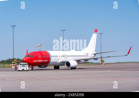 Eine boeing 737-800 von norwegischen Fluggesellschaften in typischer rot-weißer Lackierung am Flughafen Göteborg landvetter, mit dem Pushback-Truck in der Nähe. Helles s Stockfoto